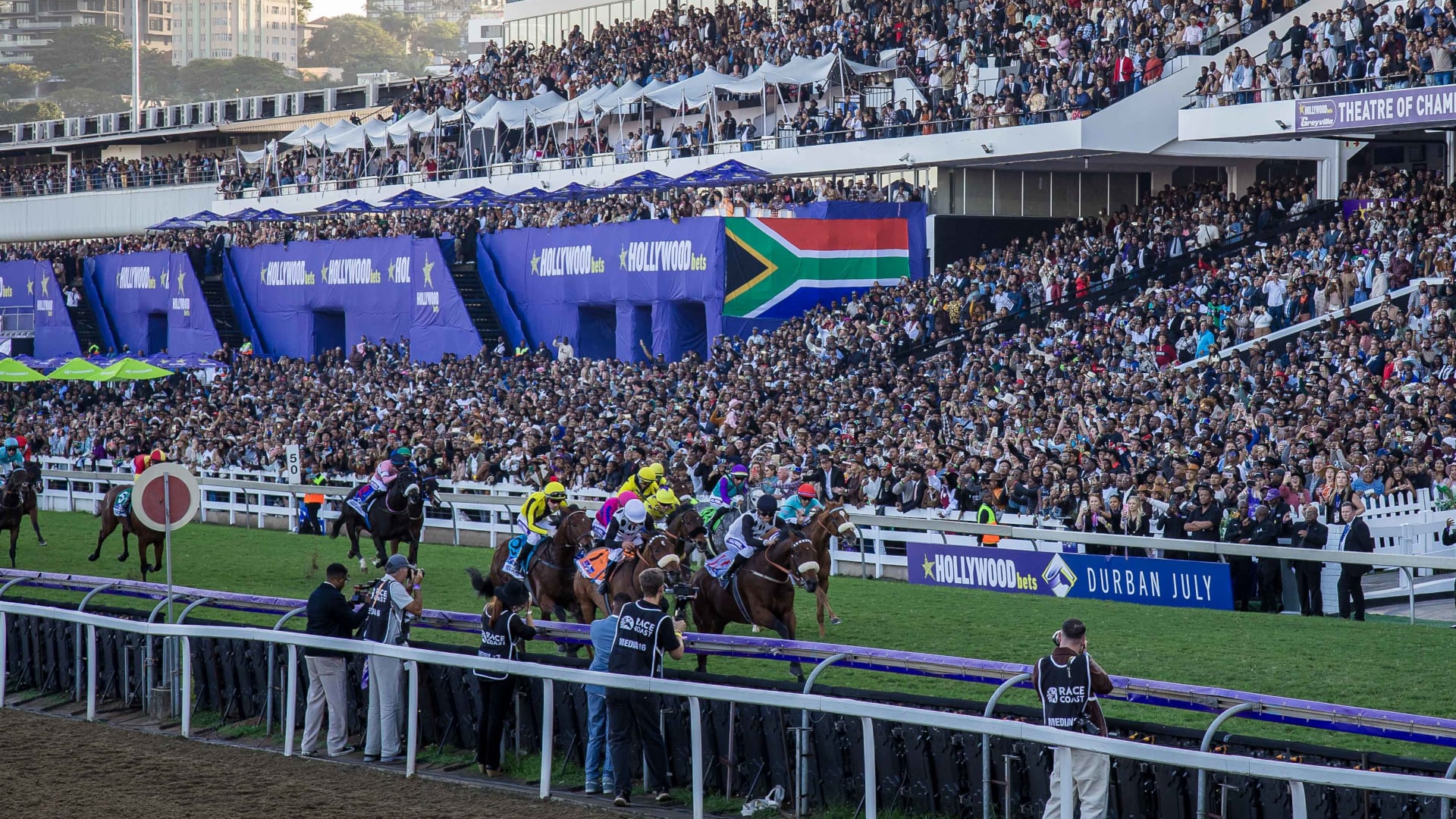 Horses racing past the packed grandstands at the Durban July